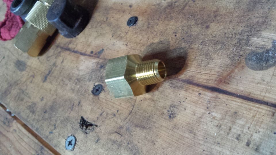 Brass pipe fitting on a wooden workbench