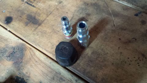 Two quick-connect air couplers and a black cap on a workbench