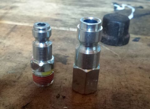 Pair of metal quick-connect air couplers on a workbench