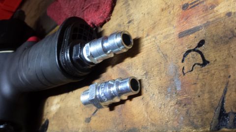 Two quick-connect air fittings on a hose near a workbench