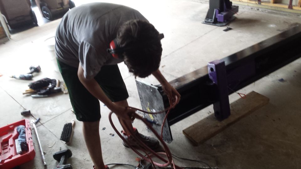 Person bending to attach hoses to a steel base on a garage floor
