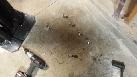 Concrete anchor bolts set in a marked square on a garage floor