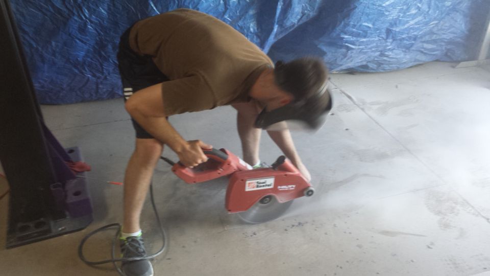 Man using a handheld concrete cut-off saw on a garage floor