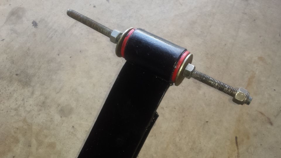 Suspension arm with bushing and threaded bolts on a concrete floor
