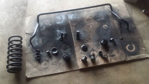 Sway bar, coil spring, and bushings laid out on cardboard