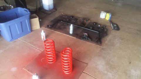 Red painted coil springs and disassembled suspension parts on garage floor