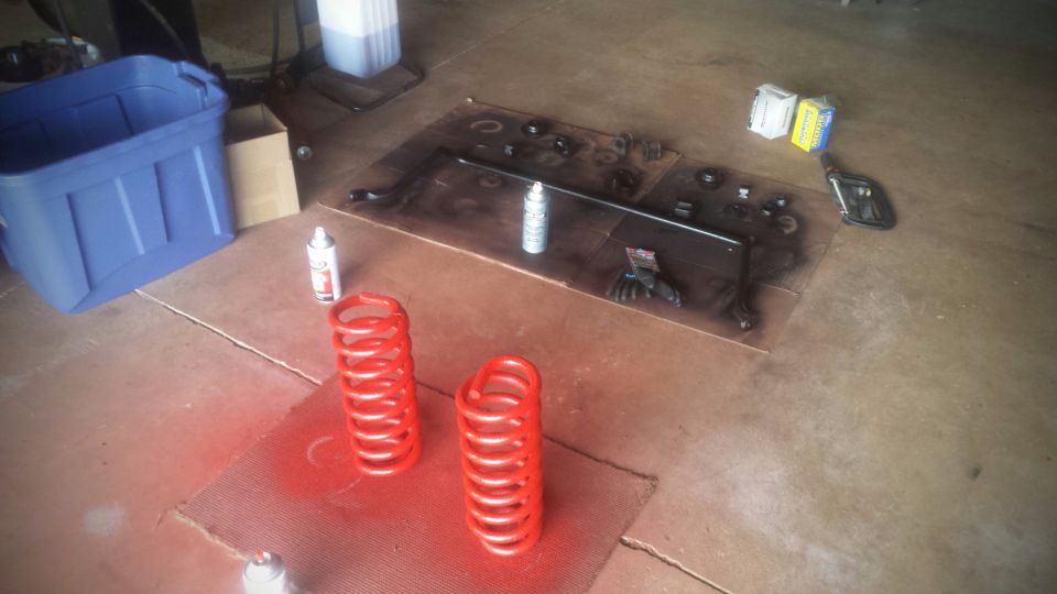 Red coil springs and disassembled suspension parts on garage floor