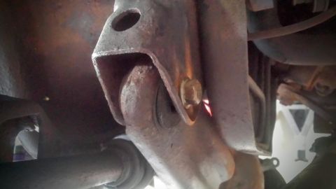 Close-up of a rusty suspension bracket and bolt under a truck