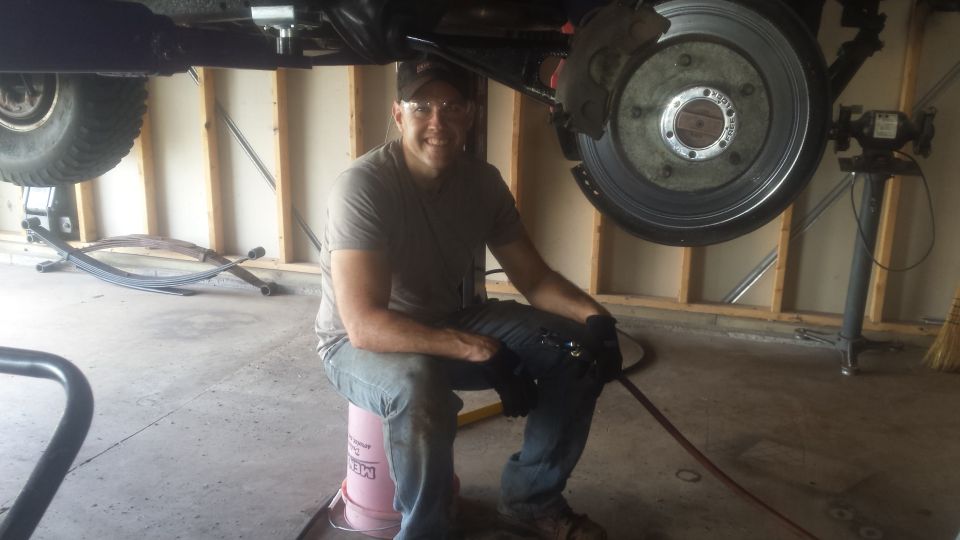Man kneeling beside a truck on jack stands during brake work