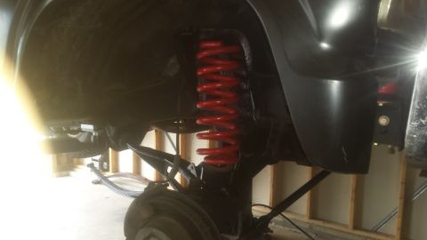 Underbody photo of front suspension with red coil spring and control arms