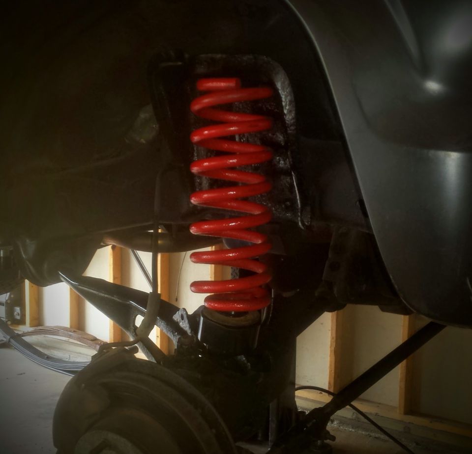 Underbody photo of a red coil spring and suspension components