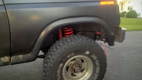 Rear quarter photo of a lifted Bronco with red rear coil spring