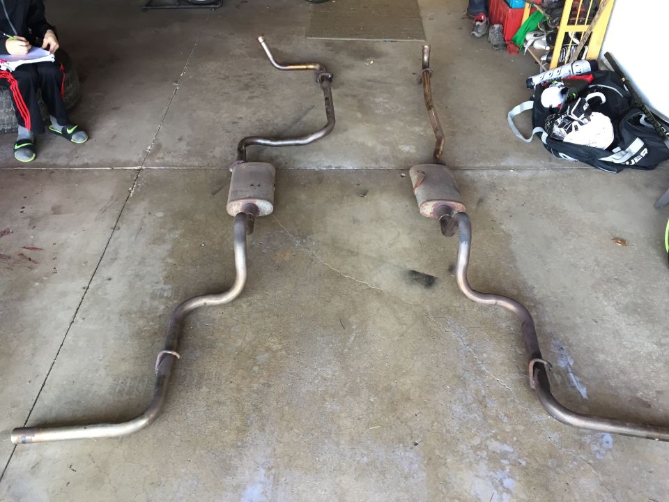 Photo of two exhaust pipe and muffler assemblies on a garage floor
