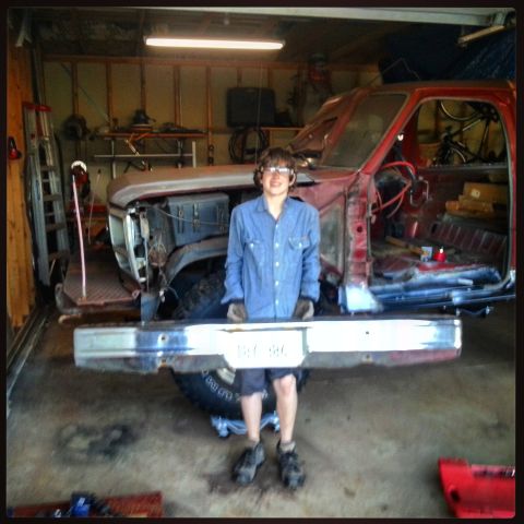 Photo of a person posing with a stripped red Bronco body in a garage