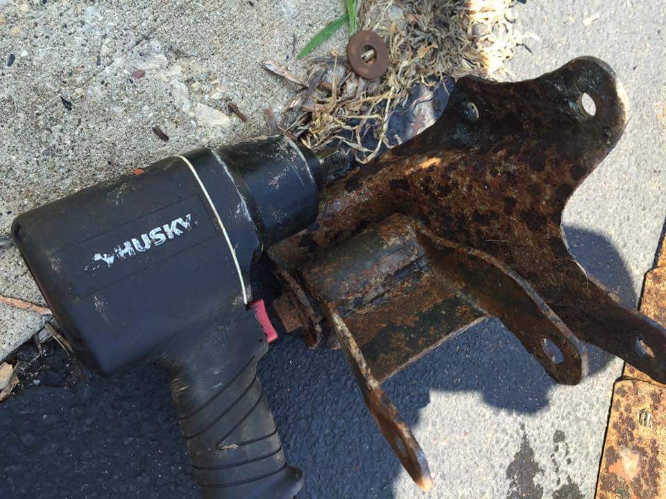 Photo of a Husky impact wrench beside a rusty steel bracket