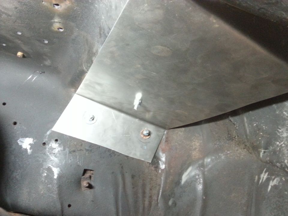 Photo of a fabricated sheet-metal floor patch bolted into a body