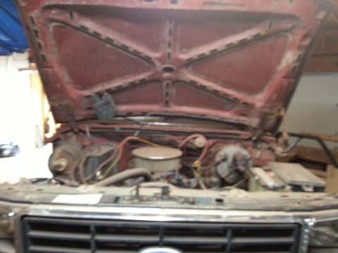 Photo of a red truck with open hood showing engine bay during restoration