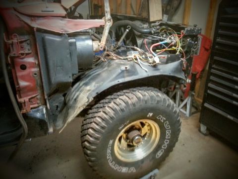 Photo of a truck front clip removed, fender and wheel with Kumho tire in garage