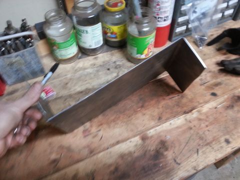 Photo of a fabricated metal bracket held over a workbench