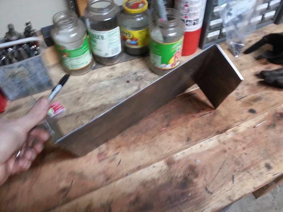 Photo of a fabricated metal bracket held over a workbench