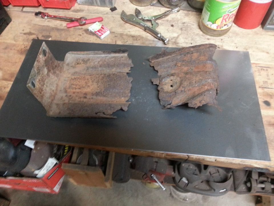 Photo of two rusted metal frame brackets on a workbench