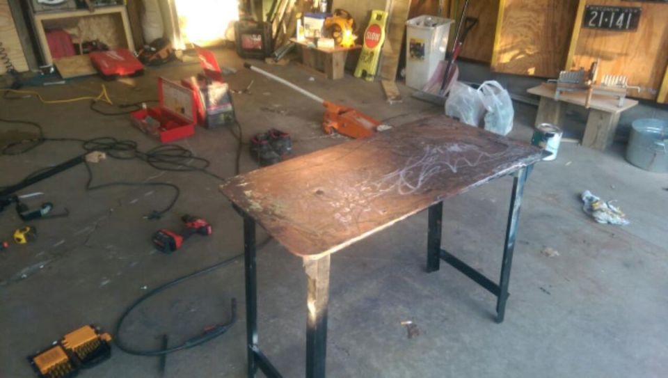 Photo of a steel welding work table in a cluttered garage