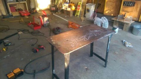 Photo of a steel welding work table in a cluttered garage