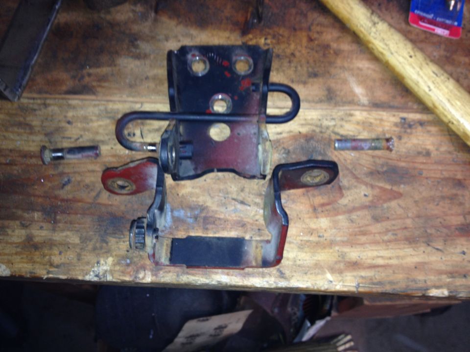 Photo of a door hinge and bracket assembly on a wooden workbench