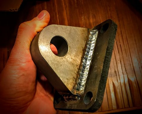 Photo of a welded steel bracket held in hand showing weld bead