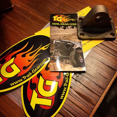 Photo of Trail-Gear stickers, a brochure, and a metal mount on a wood floor