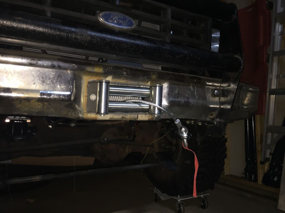 Photo of a winch mounted under a Ford truck front bumper in a garage