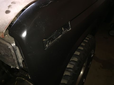 Photo of a dark Ford truck front fender and tire in a garage
