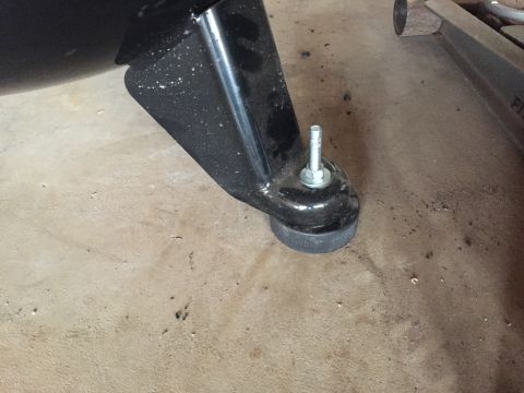 Black metal bracket bolted to a rubber mount on a concrete floor