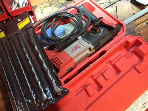Milwaukee rotary hammer drill with masonry bits in a red case