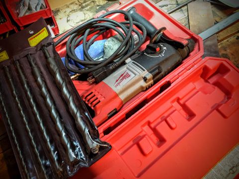 Milwaukee rotary hammer drill and masonry bits in a red carrying case