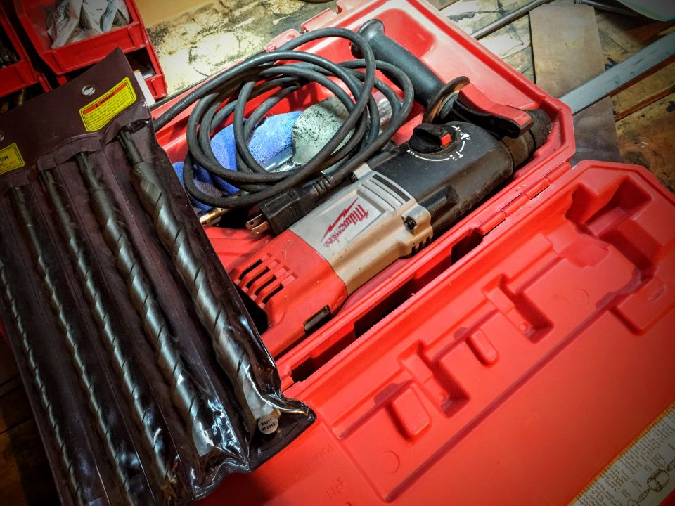 Milwaukee rotary hammer drill and masonry bits in a red carrying case