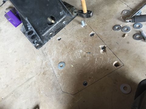 Metal mounting plate with bolt holes and washers on a concrete floor