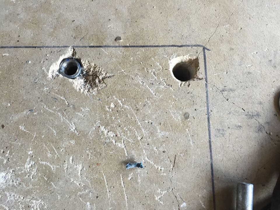 Drilled anchor holes in a concrete floor with marked layout lines