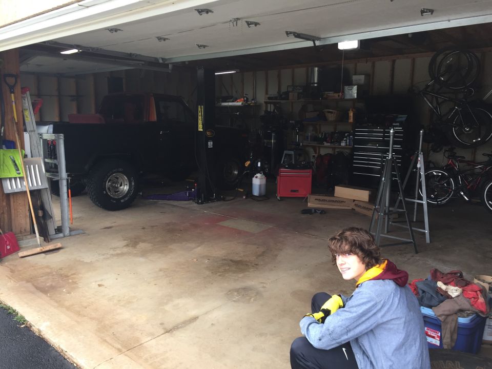 Garage interior with two vehicles, one possibly a truck, and two people