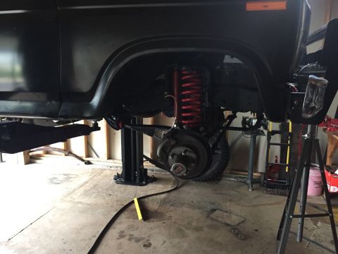 Black SUV chassis on lift, showing suspension and red coil spring