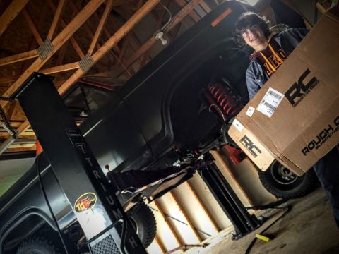 Black Ford Bronco interior with a person holding a Rough Country suspension box