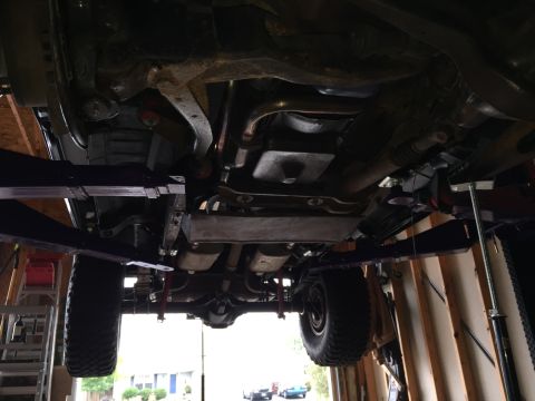 Underside view of a truck on a lift showing frame and driveline