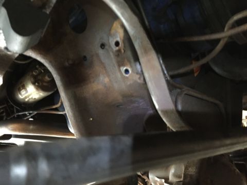 Underside view of a vehicle frame section with drilled holes