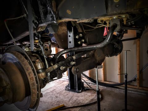 Front axle, brake disc and steering linkage under a lifted truck
