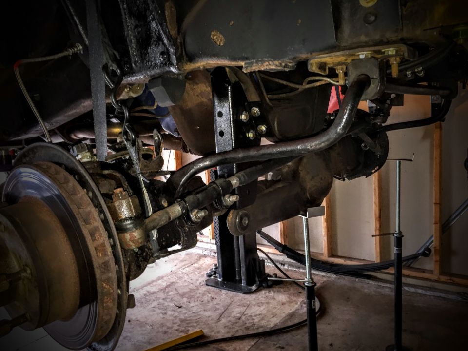 Front axle, brake disc and steering linkage under a lifted truck
