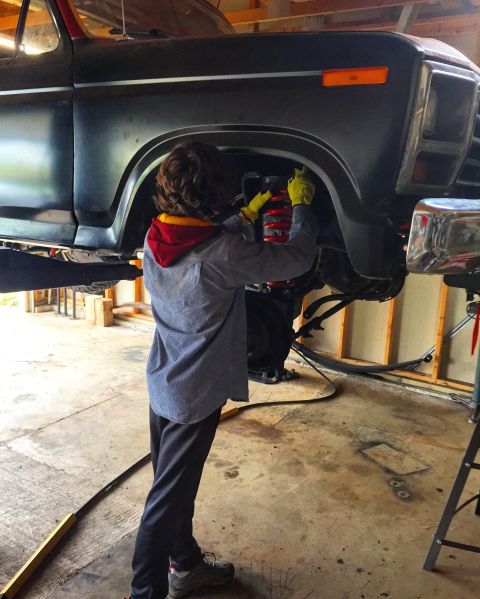 Person using an impact wrench on the front wheel well of a truck