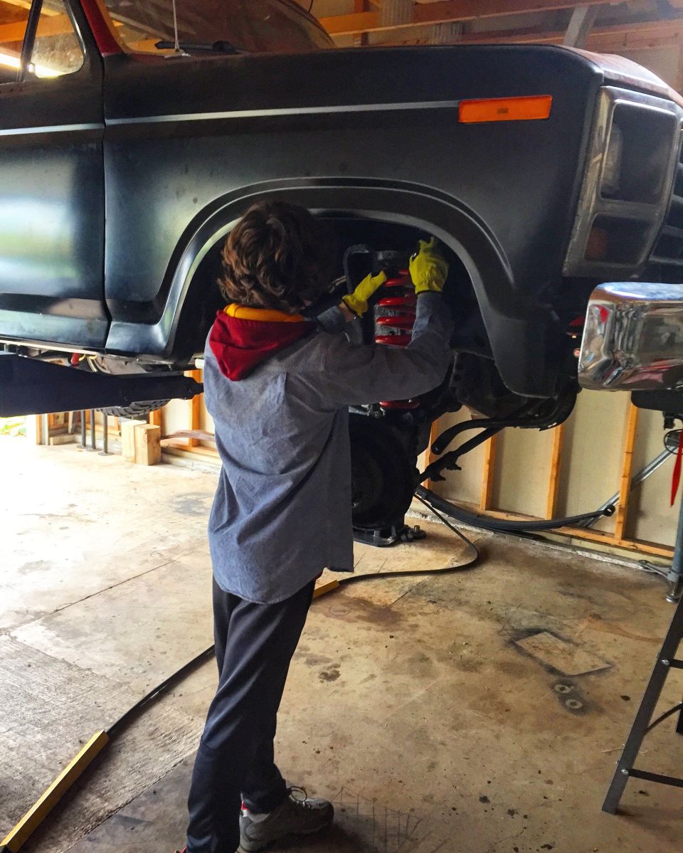 Person using an impact wrench on the front wheel well of a truck