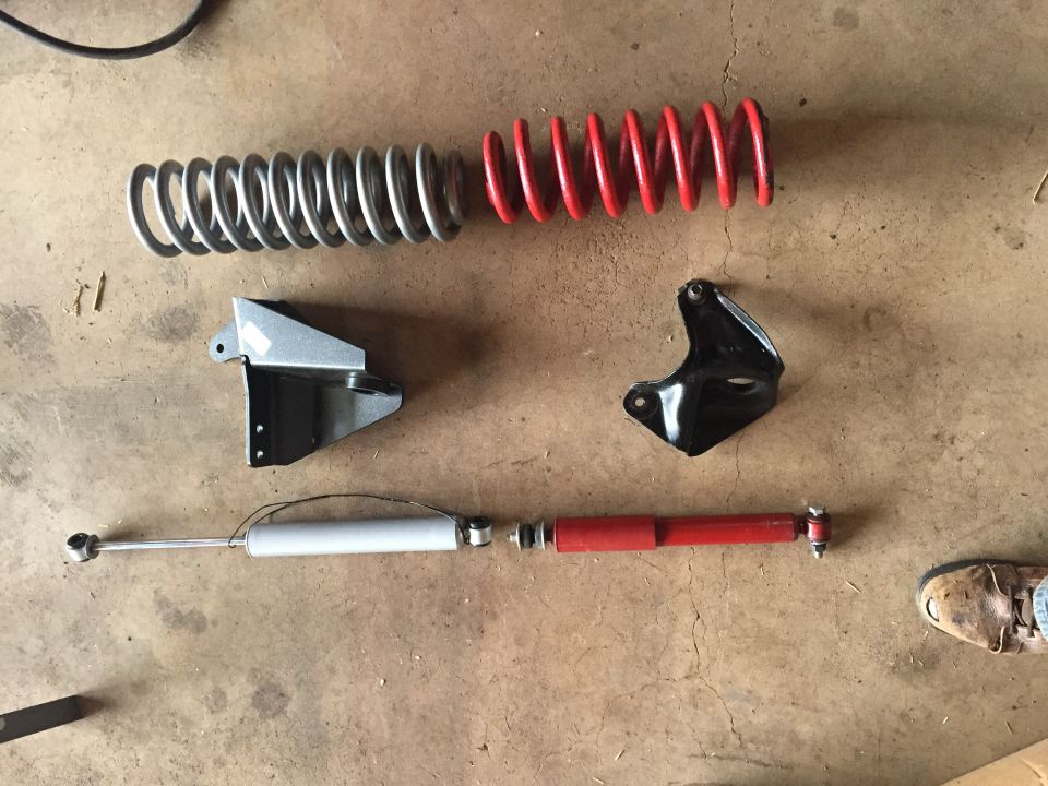 Coil springs, mounting brackets, and shock absorbers laid out on a garage floor