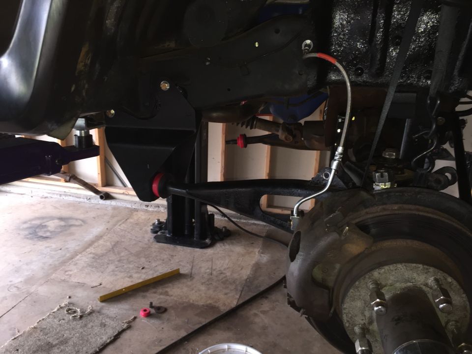 Underside view of a truck on a lift showing front suspension and brake hub