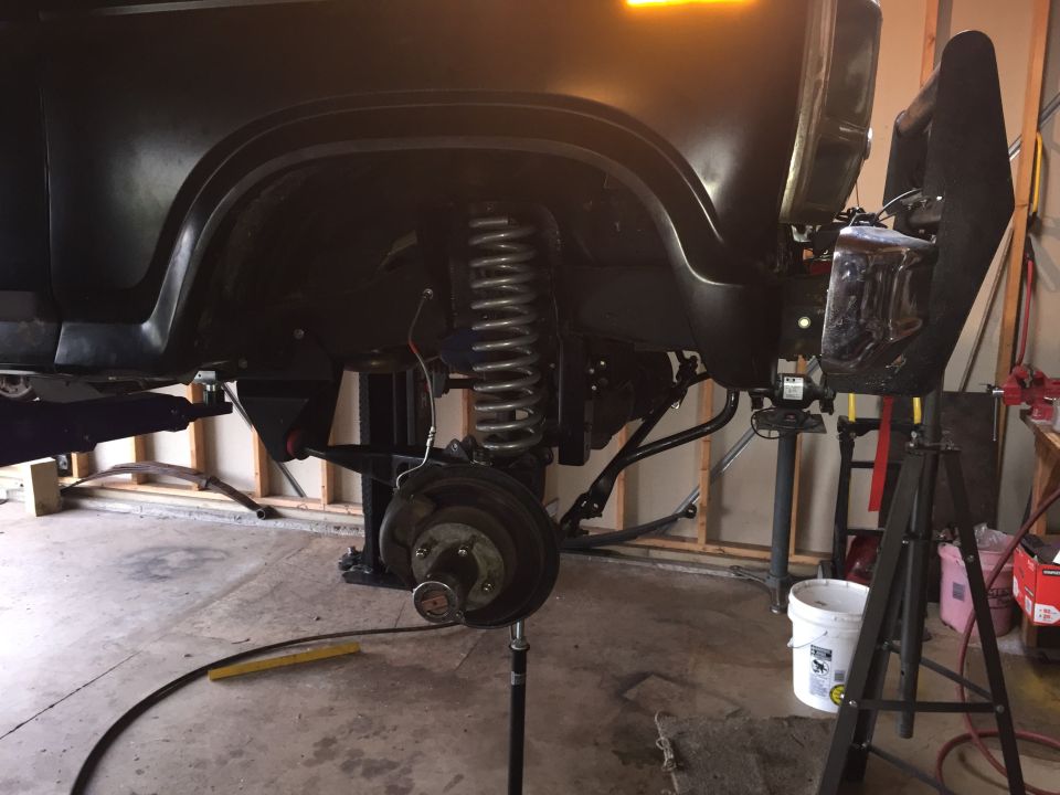 Front suspension with coil spring and brake drum on a truck raised in a garage